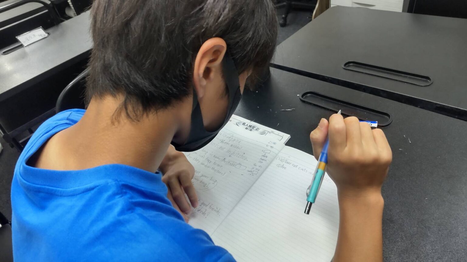 机に向かって勉強する中学生の後ろ姿
